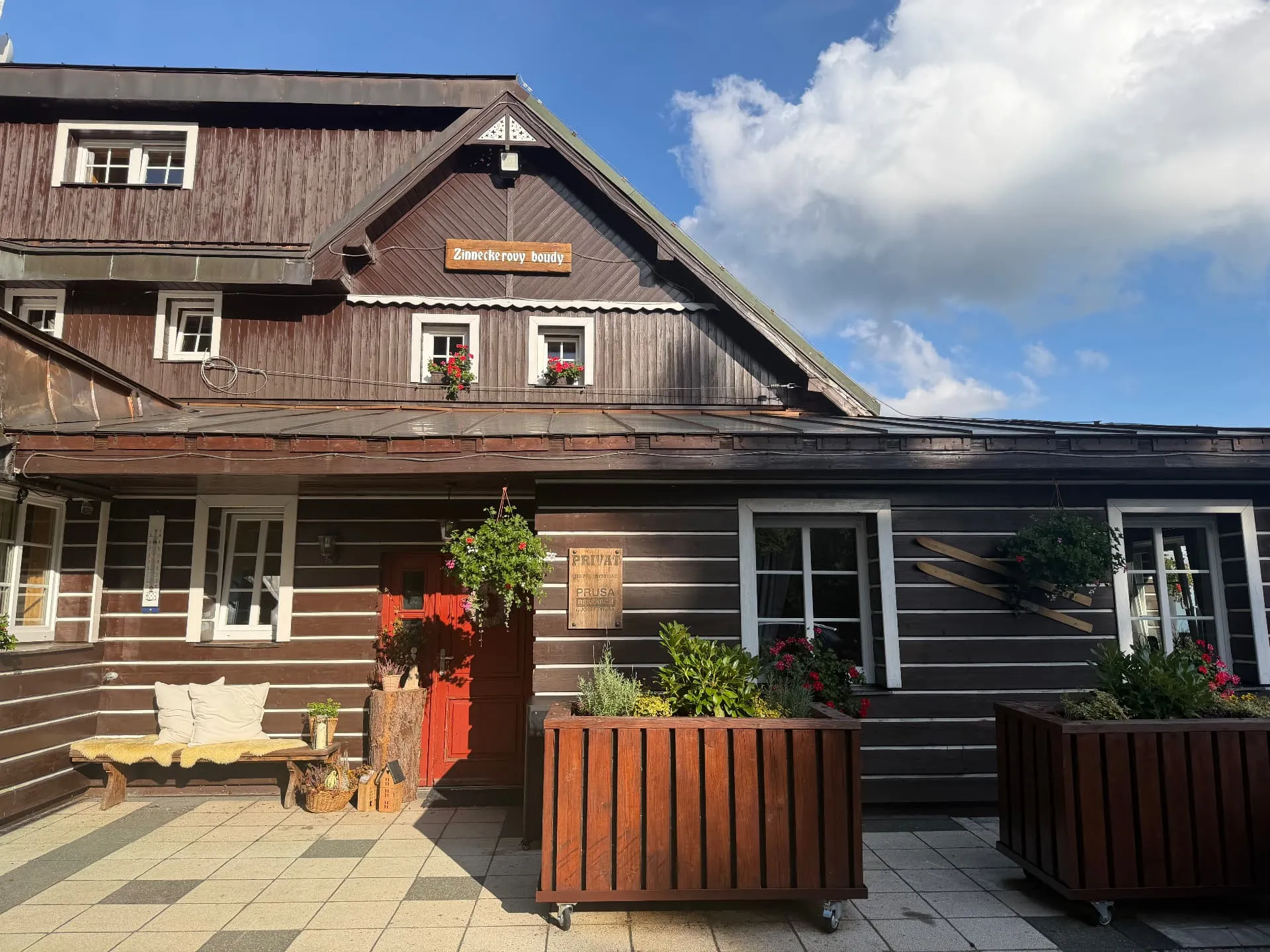 Fasáda chaty Zinneckerka s cedulí a květinami
